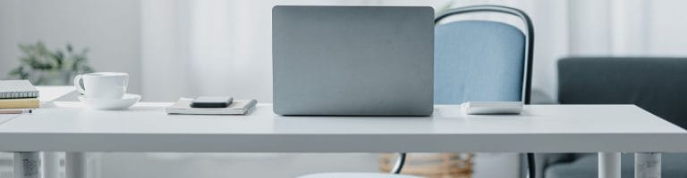office desk with a laptop and notebook on top.