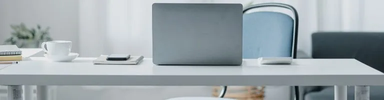 office desk with a laptop and notebook on top.